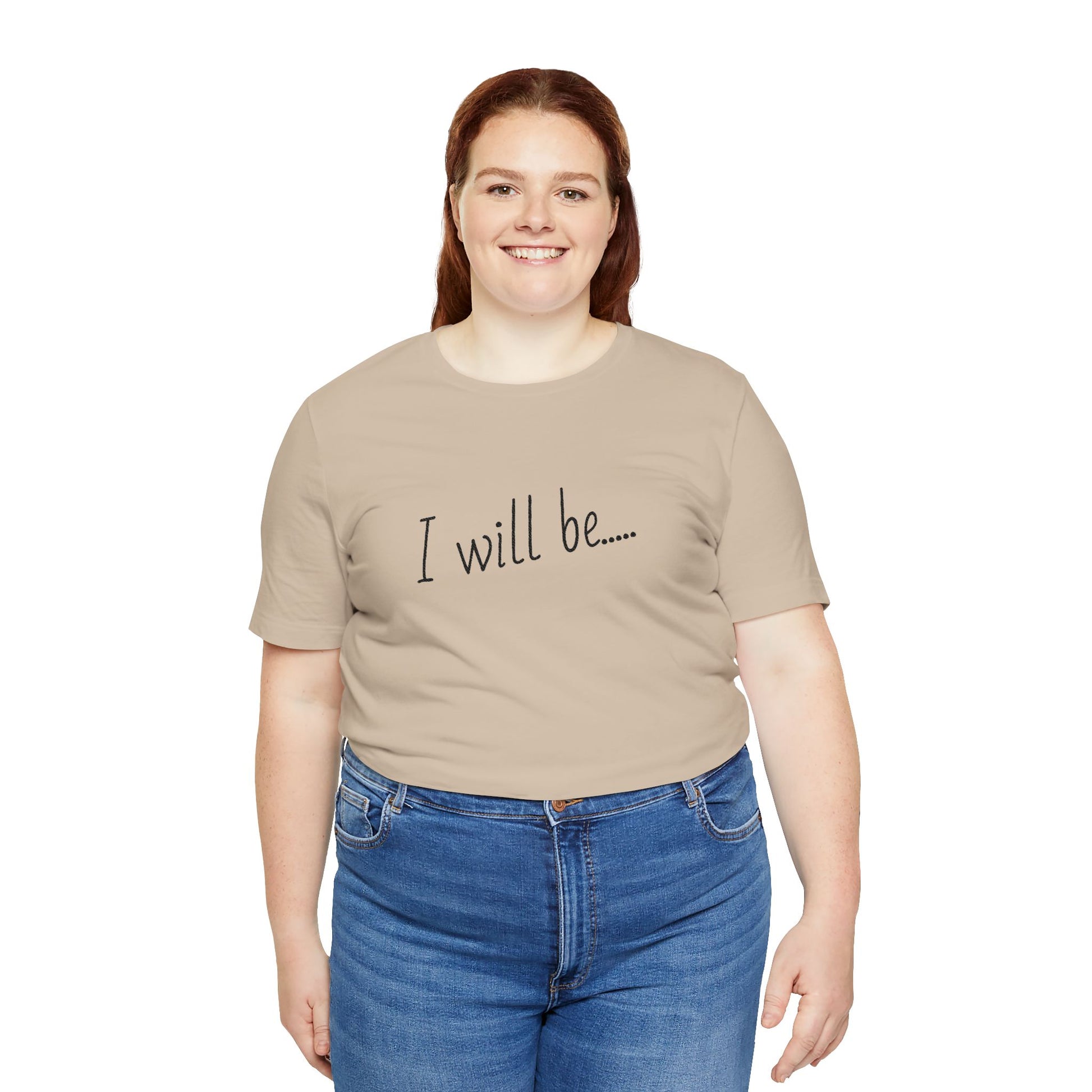 Person wearing a beige t-shirt with 'I will be...' text and blue jeans on a white background