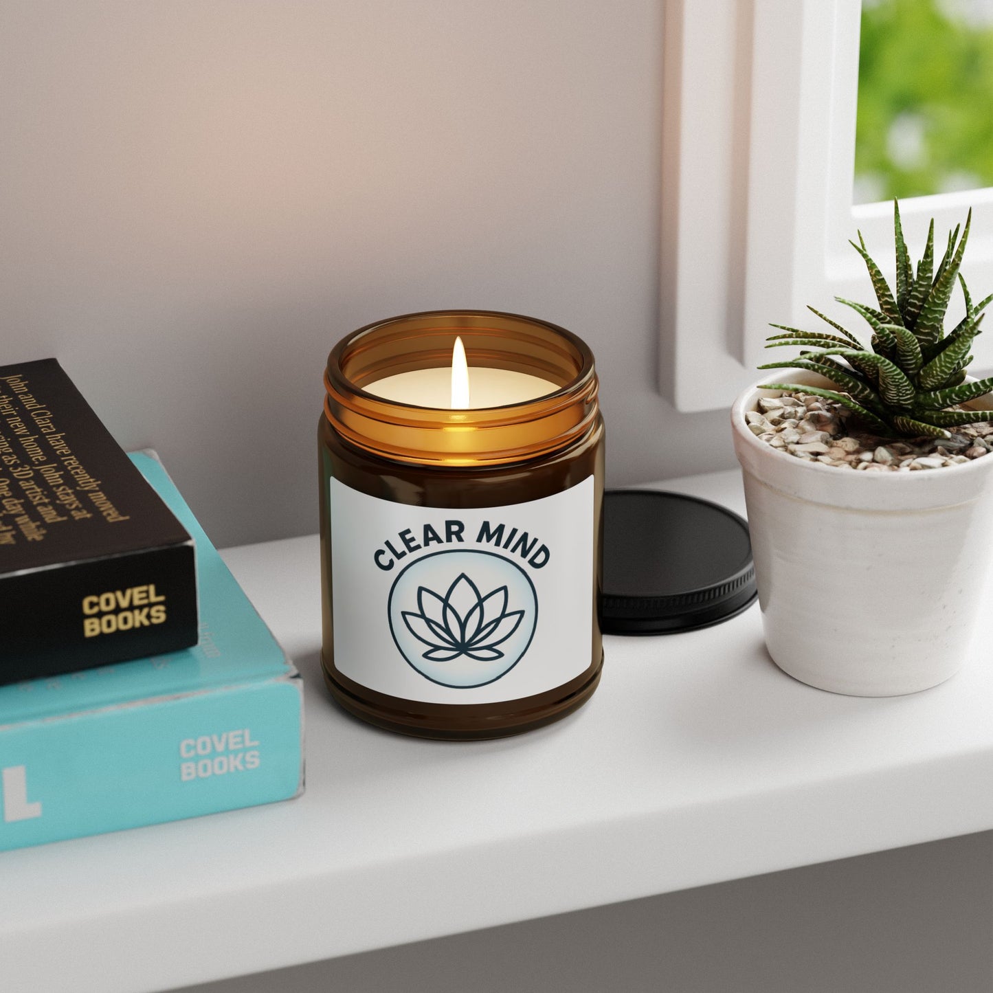 Candle labeled 'Clear Mind' on a shelf with books and a plant