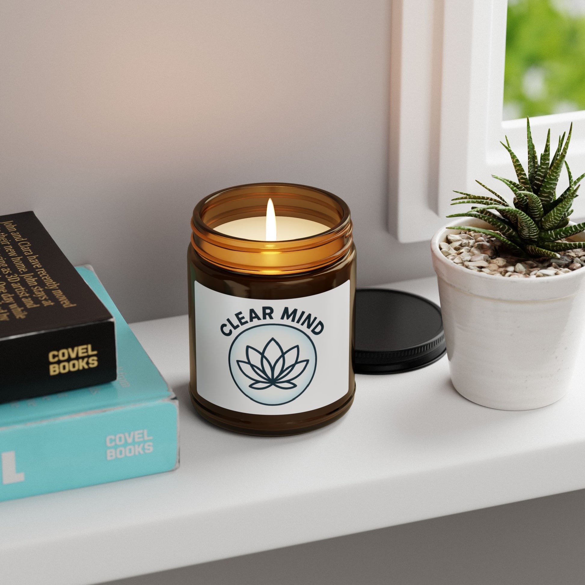 Candle labeled 'Clear Mind' on a shelf with books and a plant